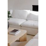 Close-up of white sofa in a light-filled room with wooden coffee table and books nearby