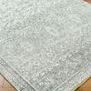 Close-up of textured rug pile highlighting faded floral pattern on hardwood floor