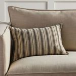 Rectangular striped pillow styled on beige upholstered couch with neutral decor backdrop