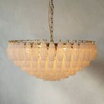 Tiered Murano-style chandelier with faceted opaline glass prisms on polished brass frame, glowing softly