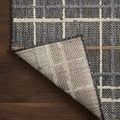 Corner of Rainier plaid rug flipped to reveal woven backing on dark wood floor