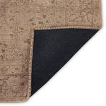 Rug corner folded to reveal black non-slip backing and stitched beige edging
