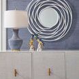 Conor Classic Lamp on light wood cabinet beneath circular white wall mirror in textured blue wallpapered room