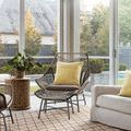Isle Indoor/Outdoor rug styled in bright living room with rattan chair, yellow pillows, large windows, and outdoor view