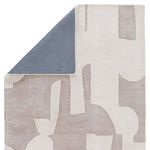 Corner flipped to reveal solid gray fabric backing on the taupe and cream rug