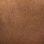 Macro texture of caramel leather upholstery showing subtle grain and finish