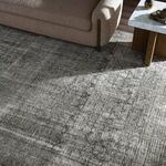 Rug styled in a living room under beige sofa and wooden coffee table with natural light