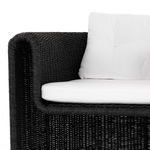 Angle showing wicker chair arm and tufted cushions emphasizing texture contrast