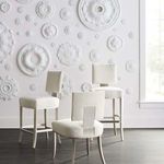 Three bar stools styled in room with decorative white medallions on wall and natural light through window
