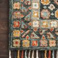 detailed close-up of rug edge with floral pattern and multicolored wool tassels on wood flooring