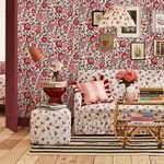 Strawberry Garden wallpaper applied on room walls with floral-patterned sofa, striped rug, and framed artwork