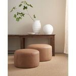 Two leather ottomans of different sizes styled in neutral room with wooden bench and white vases