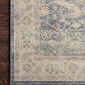 Close-up of Hathaway Denim / Multi rug edge on dark wood floor highlighting floral pattern and stitched border