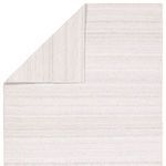 Rug corner folded back exposing backing side with diamond trellis pattern in gray and white