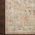 Close-up of rug's corner on dark wood floor highlighting fine weave and muted apricot floral border