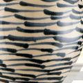 Close-up of the lamp's ceramic base showing blue fish-like brush strokes and crackle finish on beige background