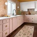 Giada Blush / Multi Rug with blush-toned floral motifs displayed in a modern kitchen with pink cabinets and dark wood floo...