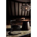 Dark moody environment highlighting table with black spindled chair and dramatic chandelier shadows