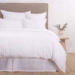 Front view of bed neatly made with Blake White/Ocean Duvet on beige linen bed skirt and headboard
