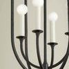 Close-up on cream candle-style bulbs and black iron arms inside lantern cage