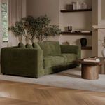 Olive sofa in living room with fireplace and minimal modern décor centered in the image.