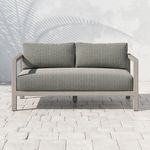 Front view of Sonoma 60-inch outdoor sofa on stone patio with shadowed wall background