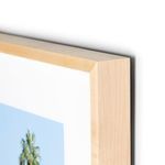 Close-up of light wood frame corner with visible grain around the framed photograph
