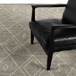 Black leather chair highlighting contrast with soft textured grey rug underneath