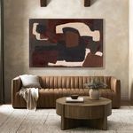 Abstract painting displayed above tan leather sofa with cushion, throw, round wooden coffee table, vase