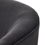 Side view capturing silhouette of curved armrest and cushioned seat