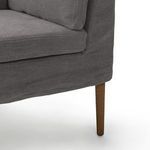 Close-up angle of lower banquette edge focusing on fabric skirt with stitched seams over tapered wood leg