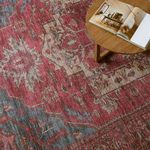 Rug detail beneath round wooden coffee table with open book, highlighting floral motifs