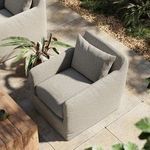 Outdoor setting with Dade Swivel Chair on tiled patio surrounded by greenery and wooden table