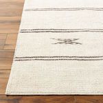 Close-up of Rivi Rug edge showing woven texture and machine stitching on wood floor