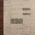 Close crop showing soft textile fibers and charcoal rectangular pattern on taupe rug