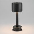 Traverse lamp turned on with warm light glowing softly from beneath black metal shade on base