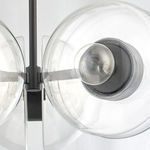 Side view showing black brass arm connecting to the clear glass globe shade