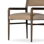 Close-up of rounded wooden front leg and connection to beige fabric seat cushion