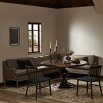 Styled dining room scene with L-shape banquette around round wooden pedestal table and metal chairs.