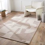 Rug styled under white armchair on natural wood floor in a bright room with white wall panels