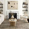 Living room scene with rug under wood coffee table, white couch, and a modern armchair near fireplace