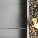 Partial interior close-up showing two glass shelves and brushed silver frame in floral wallpaper setting