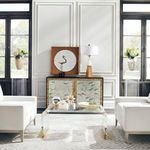 Two clear acrylic pedestals in elegant living room holding vases, with a curved acrylic coffee table in foreground
