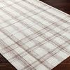 Angled view of rug on dark hardwood floor highlighting flatwoven texture and plaid design