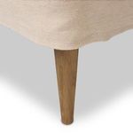 Side profile in bright room, highlighting winged back, tapered legs, and fabric texture