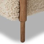 Close-up of tapered oak turned leg supporting plush shearling seat cushion