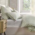 Side view of bed with duvet slightly turned down, showing matching shams and bedside table lamp