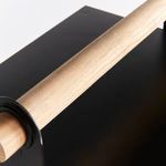 Extreme close-up of the smooth teak wood handle resting on the matte black metal lantern top