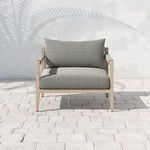 Front view on tiled patio with palm shadow casting over the chair’s cushions and frame