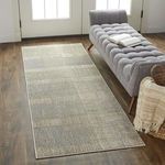 Aura Gray / Gold Rug styled in room with gray tufted chaise lounge on dark wood floor